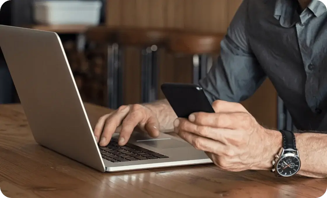 laptop oraz telefon komórkowy w dłoniach przedsiębiorcy